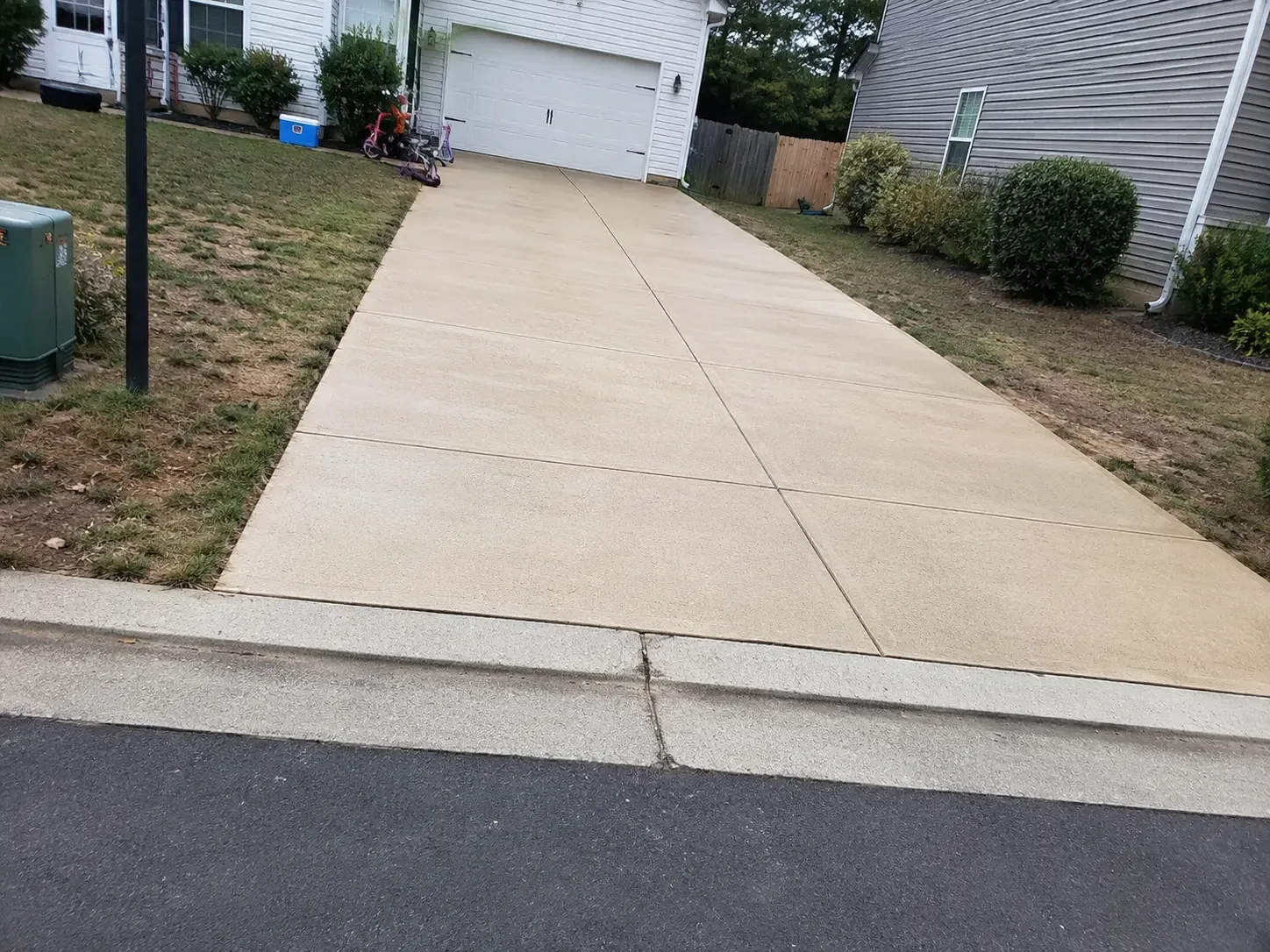 Clean concrete driveway leading to a garage in a Virginia neighborhood