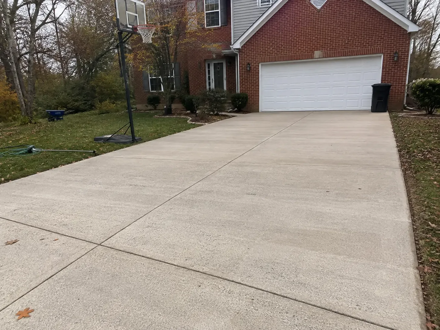 Freshly cleaned concrete driveway at a brick Virginia home