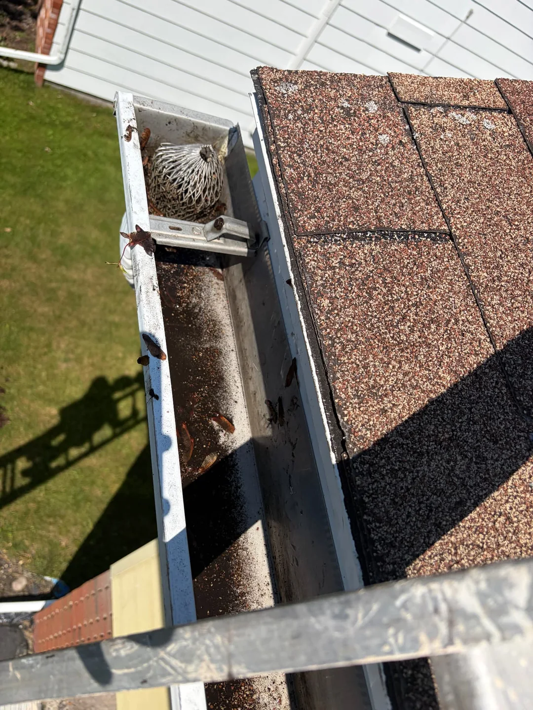 Residential gutter viewed from a ladder during gutter cleaning service