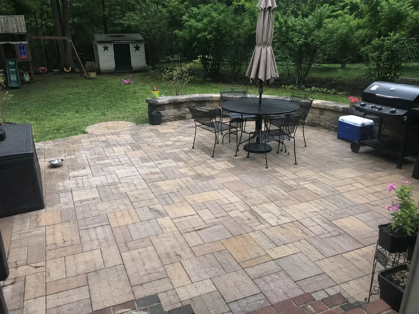 Clean backyard paver patio with outdoor furniture and grill